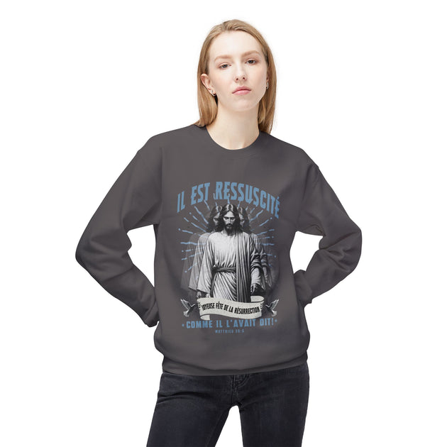 Une femme porte un sweat-shirt gris foncé avec une illustration religieuse et le texte Il est ressuscité.