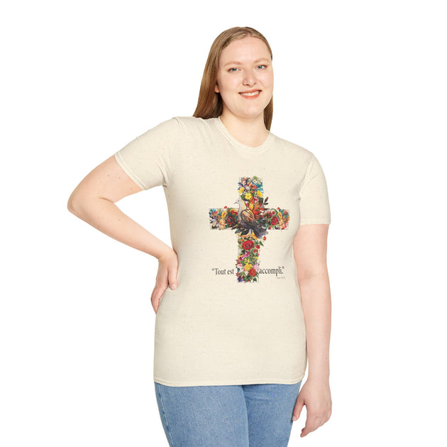 Une femme porte un t-shirt beige chiné orné d'une croix fleurie avec une colombe et le texte Tout est accompli.