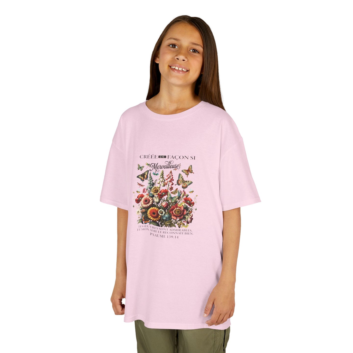 Une jeune fille porte un t-shirt rose pâle orné d'un motif floral vintage et de papillons.