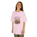 Une jeune fille porte un t-shirt rose pâle orné d'un motif floral vintage et de papillons.