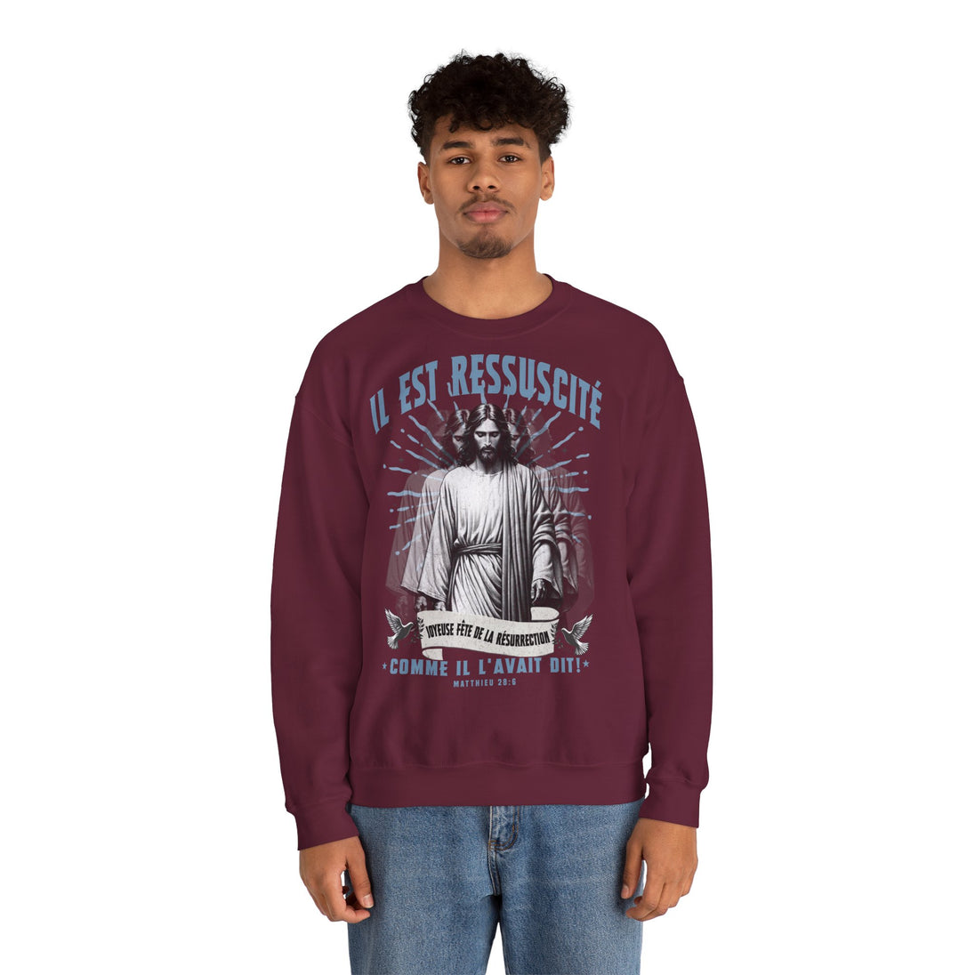 Un homme porte un sweatshirt bordeaux avec une illustration religieuse et le texte Il est ressuscité.