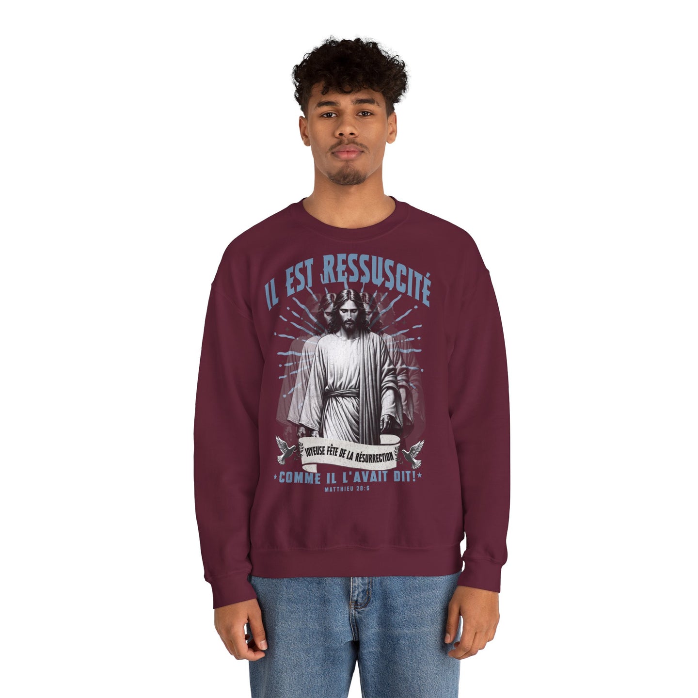 Un homme porte un sweatshirt bordeaux avec une illustration religieuse et le texte Il est ressuscité.