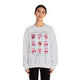 Une femme porte un sweat-shirt gris chiné orné d'illustrations de fruits et de nœuds roses.