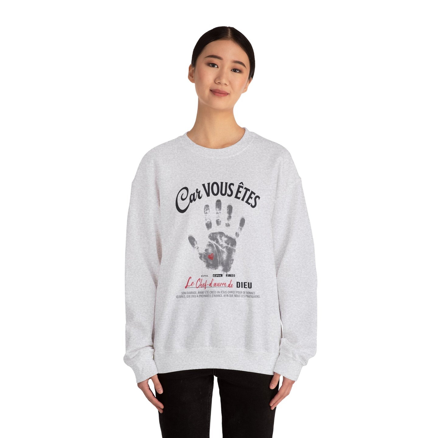 Une femme porte un sweat-shirt gris chiné avec une empreinte de main et un texte religieux.