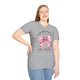 Une femme porte un t-shirt gris avec un motif de nœud vichy rose et une croix chrétienne.