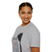 Une femme porte un t-shirt gris orné d'une silhouette de Jésus et de textes religieux en français.