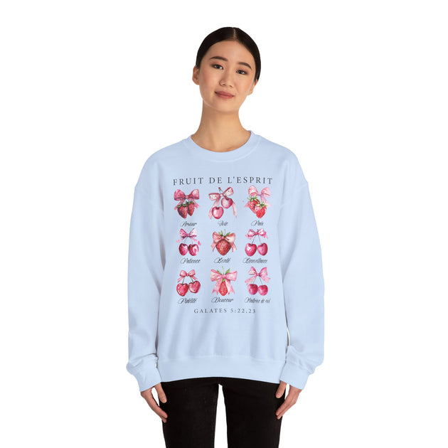 Une femme porte un sweat-shirt blanc illustré de fruits et de nœuds avec le texte Fruit de l'Esprit.