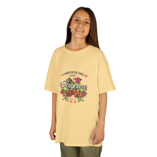Une jeune fille porte un t-shirt jaune pâle orné d'un motif floral et du texte L'Amour de Dieu.
