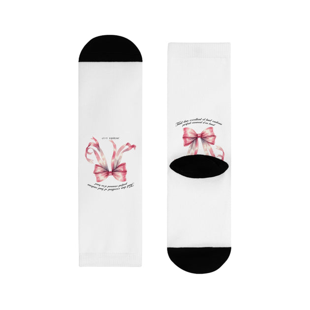 Paire de chaussettes blanches avec un motif de ruban rose et une inscription religieuse.