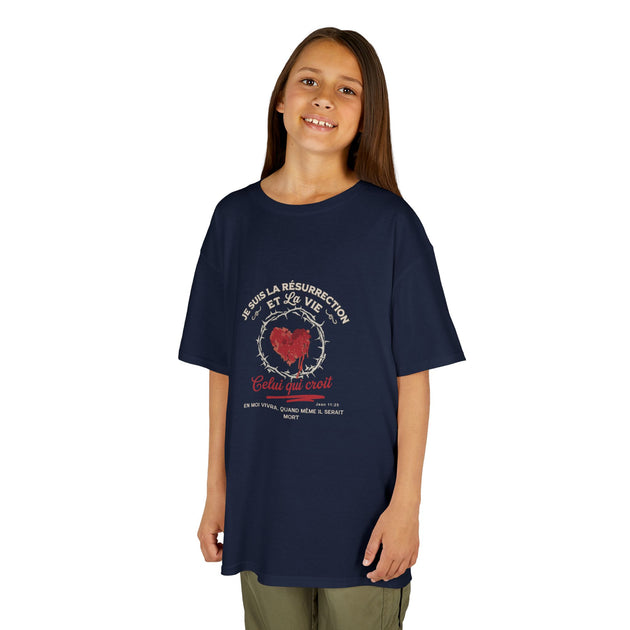 Une jeune fille porte un t-shirt bleu marine avec un motif religieux représentant un cœur épineux.