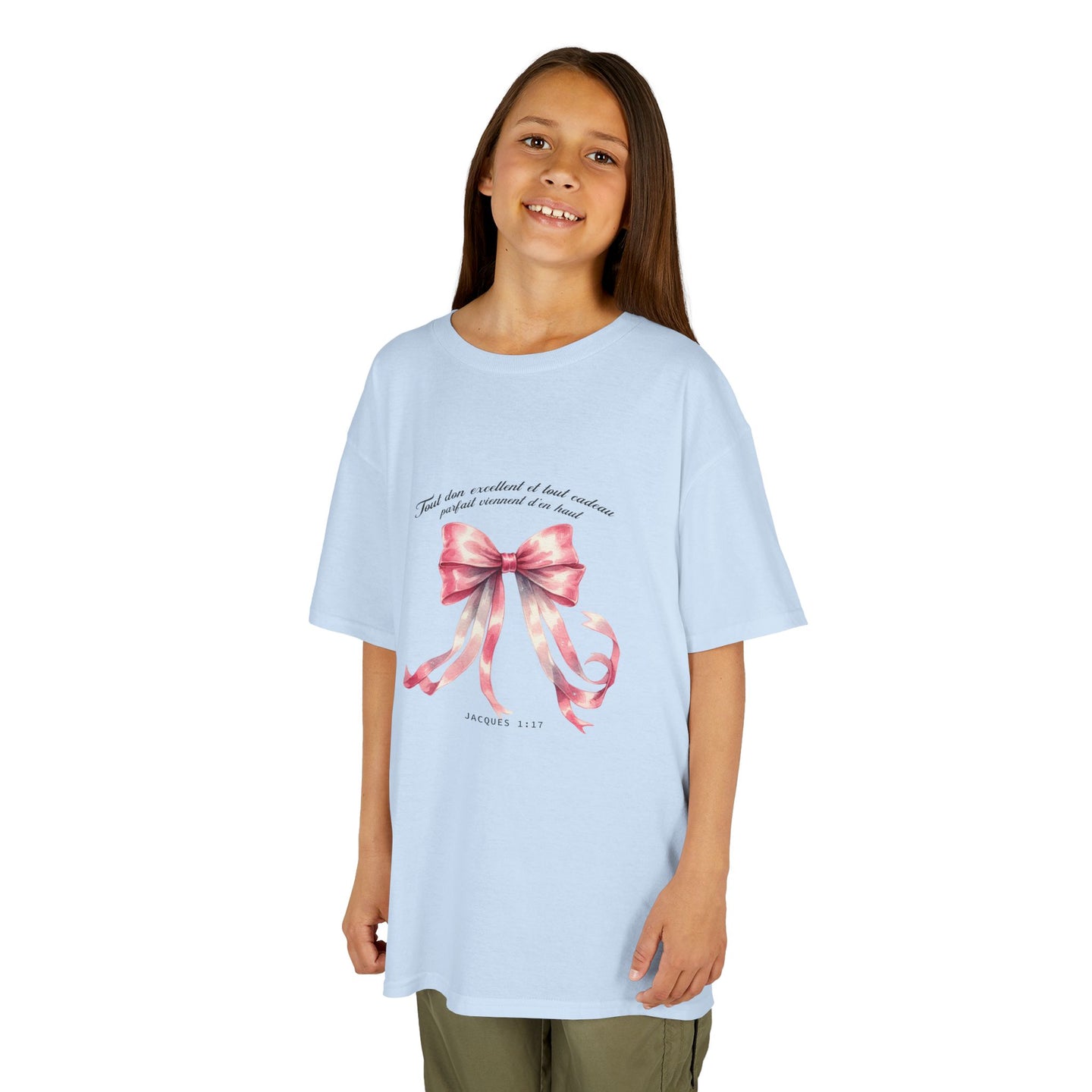 Une enfant porte un t-shirt bleu clair orné d'un ruban rose et du verset Jacques 1:17.