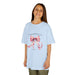 Une enfant porte un t-shirt bleu clair orné d'un ruban rose et du verset Jacques 1:17.