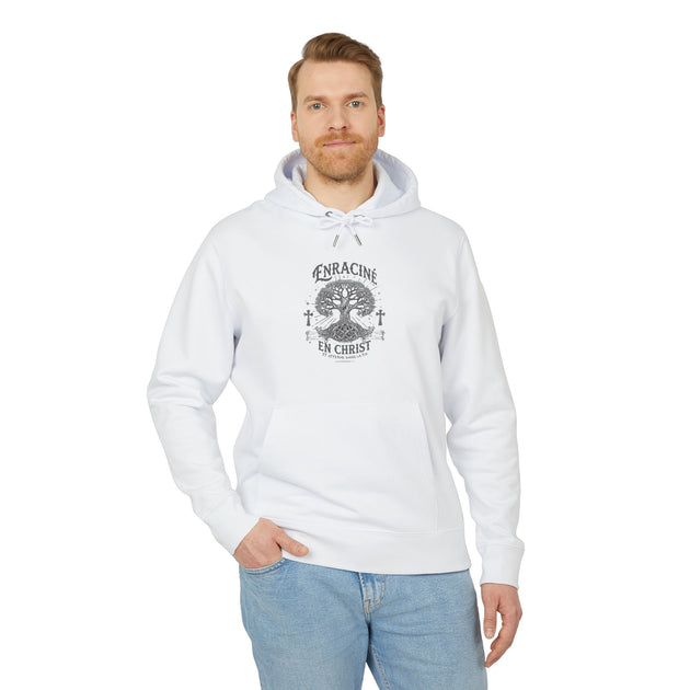 Un homme porte un sweat à capuche blanc avec un motif d'arbre et le texte Enraciné en Christ.