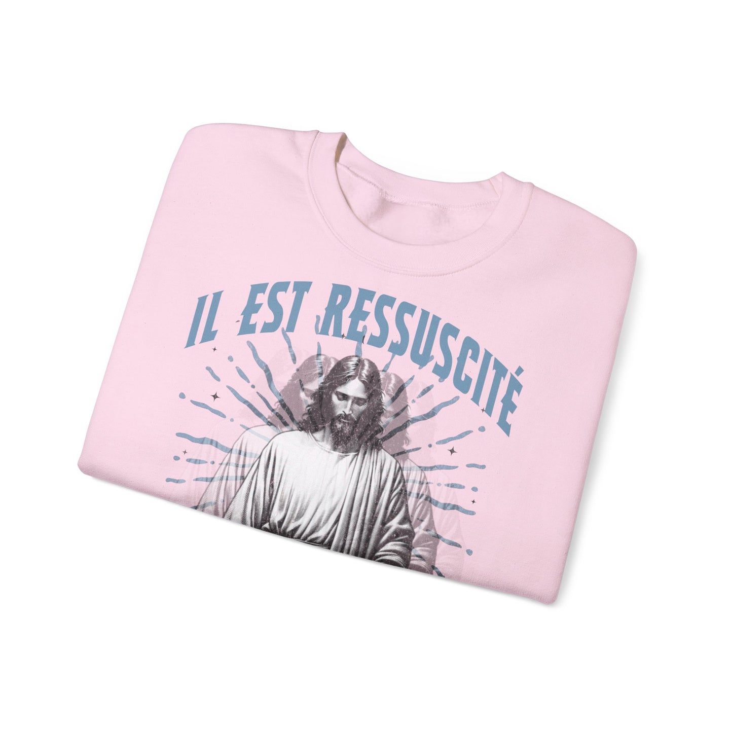 Sweat-shirt rose pâle plié avec l'inscription Il est ressuscité et une image de Jésus.
