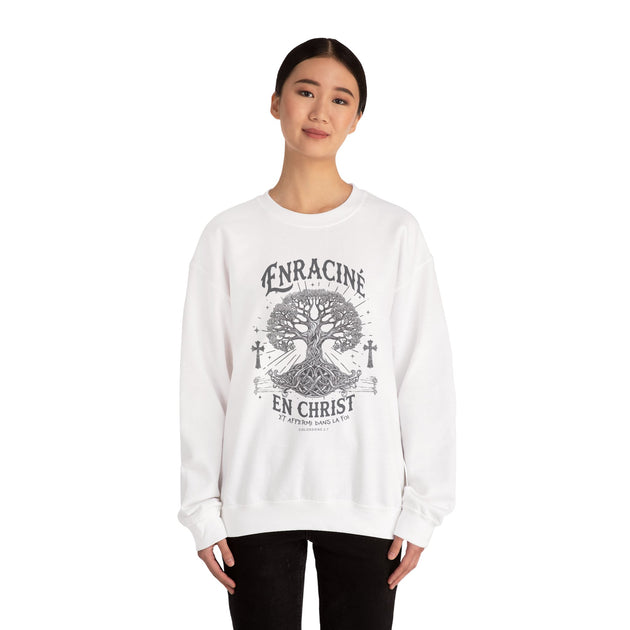 Une femme porte un sweatshirt blanc avec un motif d'arbre de vie et le texte Enraciné en Christ.