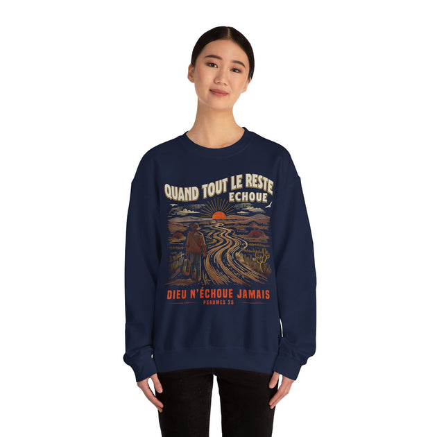 Une femme porte un sweatshirt bleu marine avec une illustration de paysage et un message chrétien.