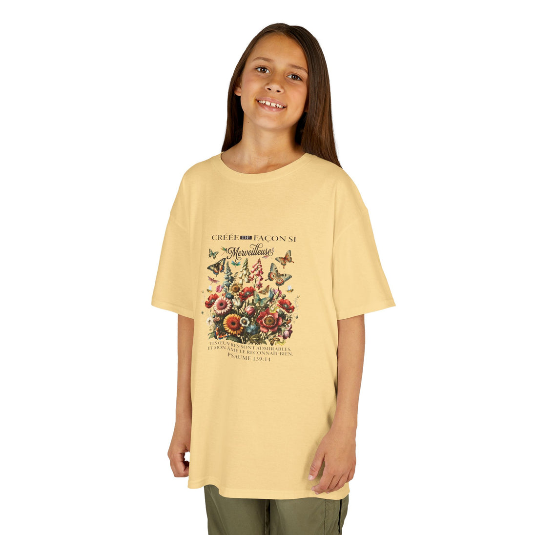 Une jeune fille porte un t-shirt jaune pâle orné d'un motif floral et de papillons.
