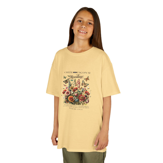 Une jeune fille porte un t-shirt jaune pâle orné d'un motif floral et de papillons.