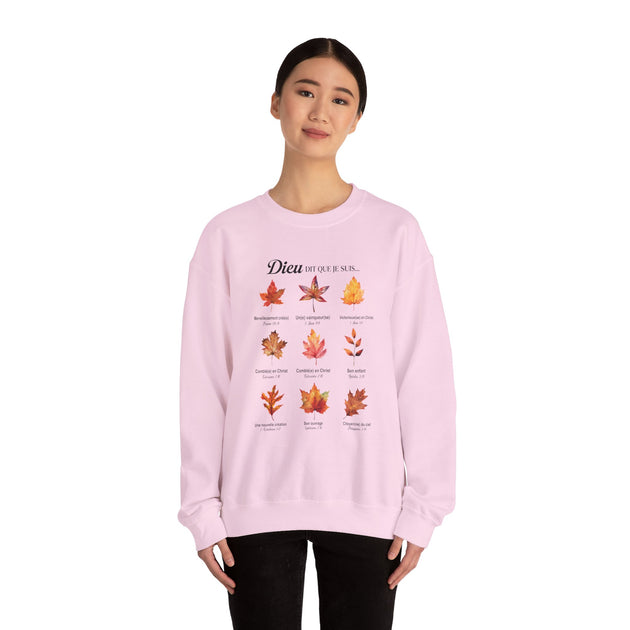 Une femme porte un sweat-shirt rose pâle orné d'un motif de feuilles et de textes bibliques.