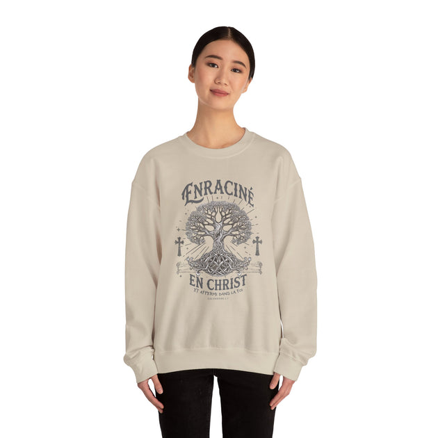 Une femme porte un sweat-shirt beige avec un motif d'arbre de vie et le texte Enraciné en Christ.