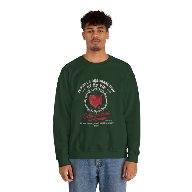 Un homme porte un sweatshirt vert foncé avec un motif religieux centré sur la poitrine.