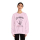 Une femme porte un sweat-shirt rose pâle avec une empreinte de main et un texte religieux.