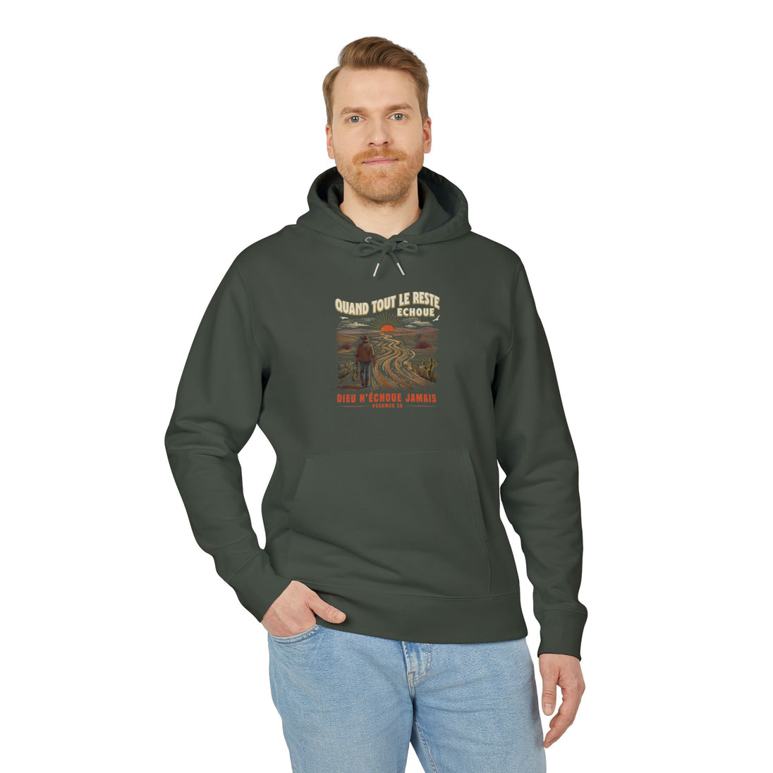 Un homme porte un sweat à capuche vert foncé avec une illustration de paysage et du texte.