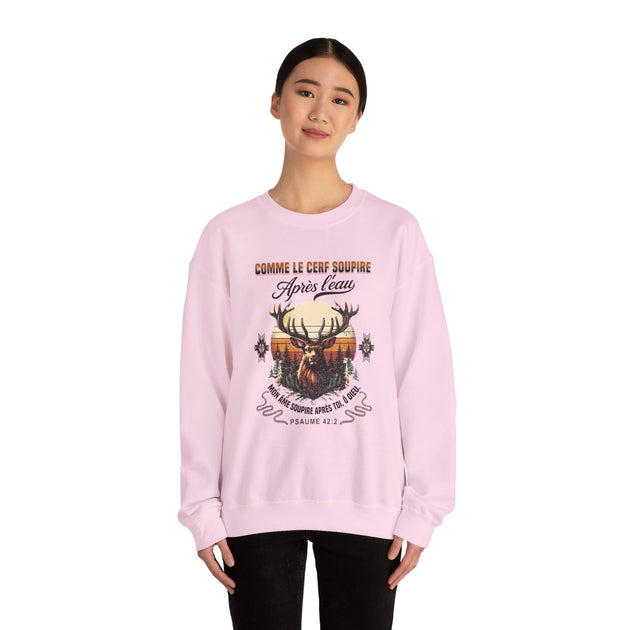 Une femme porte un sweat-shirt rose pâle orné d'un motif de cerf et du texte biblique.