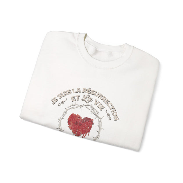 Sweat-shirt blanc plié avec un motif de cœur couronné d'épines et l'inscription Je suis la résurrection.