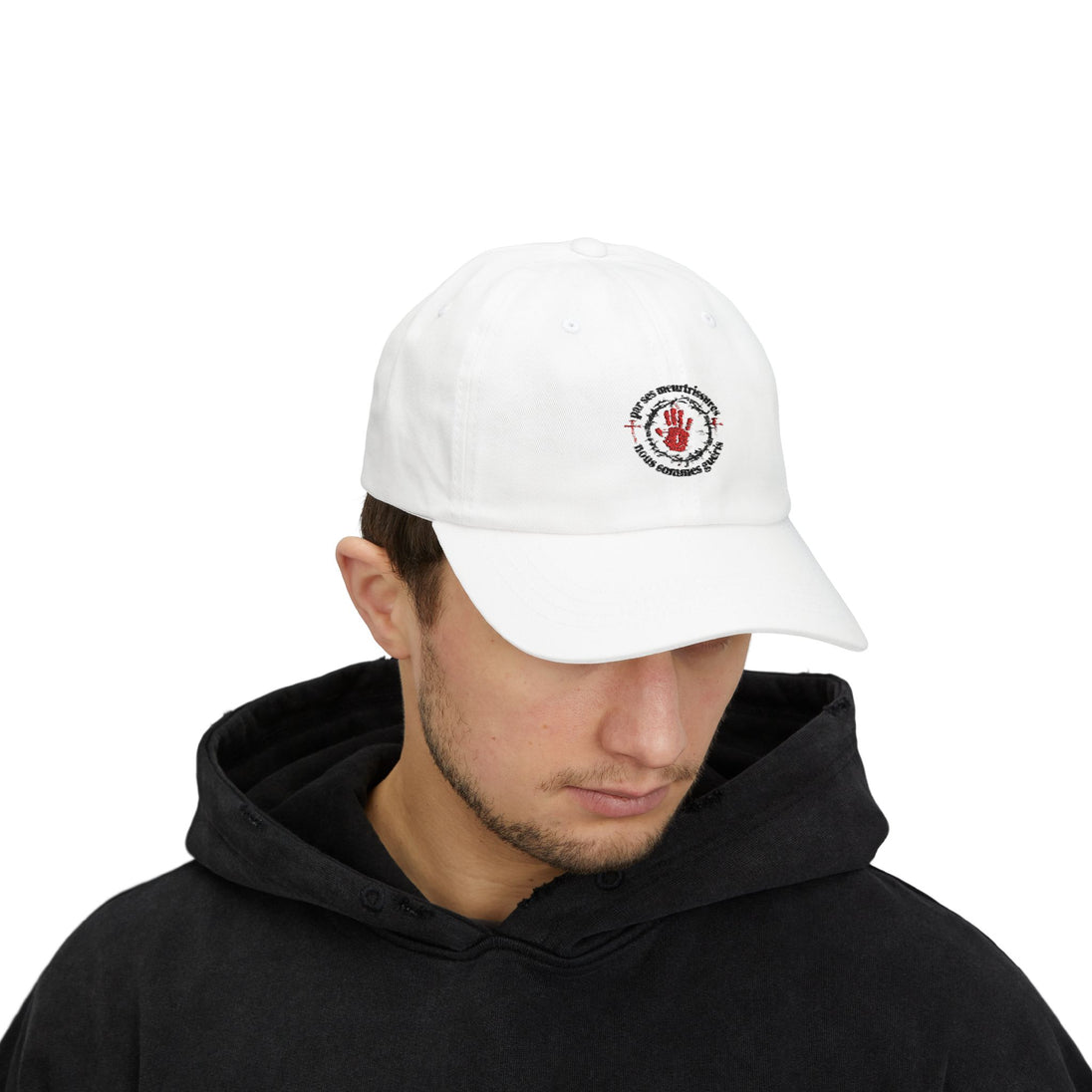 Un homme porte une casquette blanche en coton avec une broderie rouge et noire sur le devant.