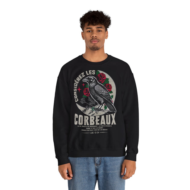 Un homme porte un sweatshirt noir avec une illustration de corbeau et un texte biblique.