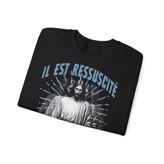 Sweatshirt noir plié avec l'inscription Il est ressuscité et une illustration de Jésus.