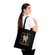 Une femme porte un tote bag noir en coton biologique orné d'une illustration religieuse.