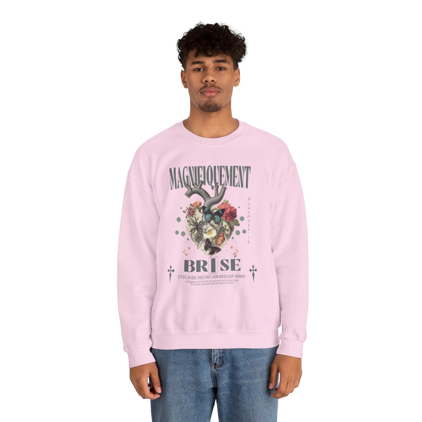 Un homme porte un sweatshirt rose pâle avec une illustration de cœur floral et un texte religieux.