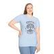Une femme porte un t-shirt bleu clair avec un motif d'arbre et l'inscription Enraciné en Christ.