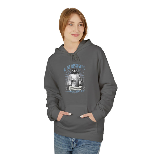 Une femme porte un sweat à capuche gris foncé avec une illustration religieuse sur la poitrine.