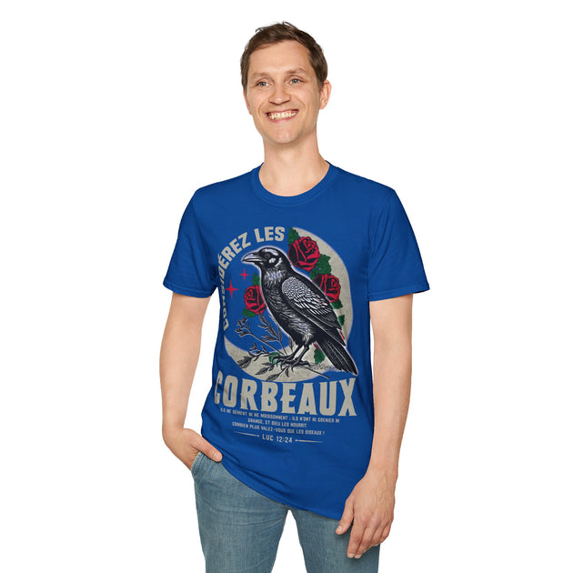 Un homme porte un t-shirt bleu orné d'un corbeau, de roses et du texte biblique Luc 12:24.