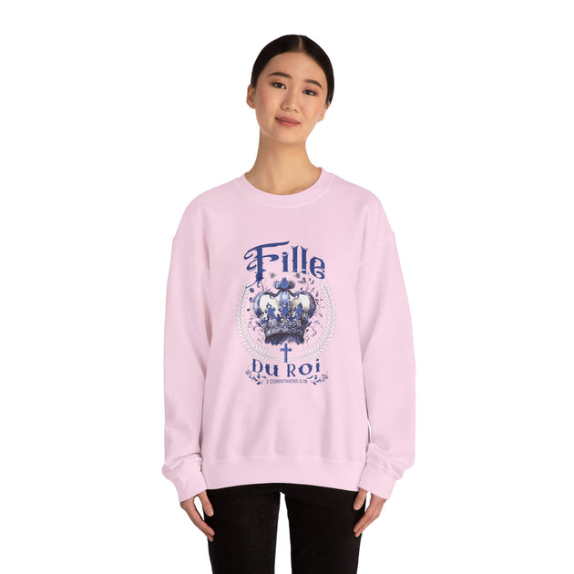Une femme porte un sweatshirt rose pâle avec une couronne bleue et le texte Fille du Roi.