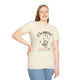 Une femme porte un t-shirt beige chiné avec une empreinte de main et un texte religieux en français.
