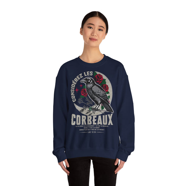 Une femme porte un sweatshirt bleu marine avec une illustration de corbeau et un verset biblique.
