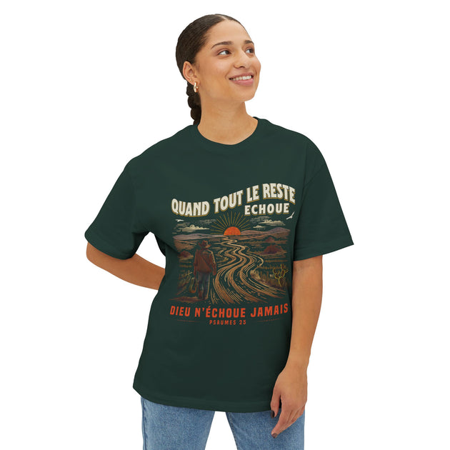 Une femme porte un t-shirt vert foncé avec une illustration de voyageur et un texte inspirant.