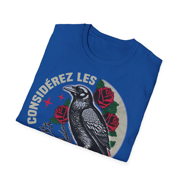 T-shirt bleu plié avec une illustration de corbeau, de roses et le texte Considérez les.