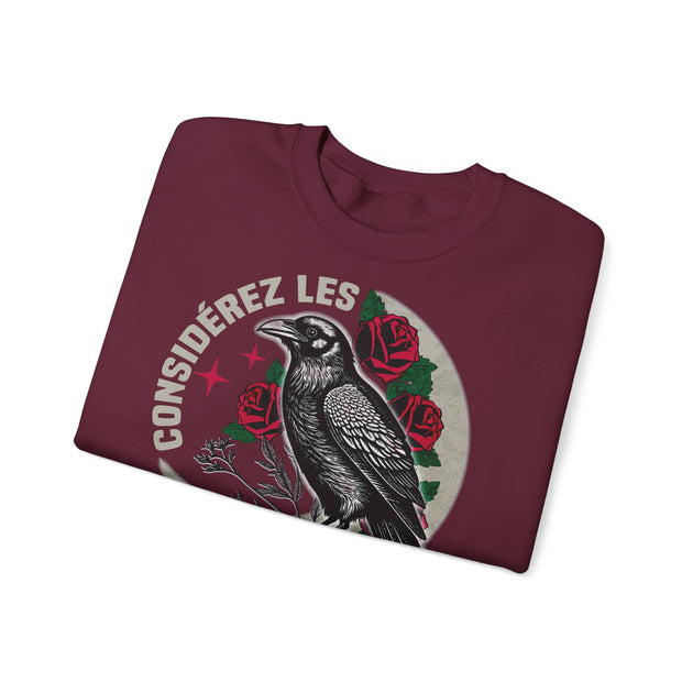 Sweat-shirt bordeaux plié avec une illustration de corbeau, de roses et l'inscription Considérez les.