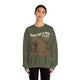 Une femme porte un sweatshirt vert olive avec une illustration de voyageur et un message chrétien.