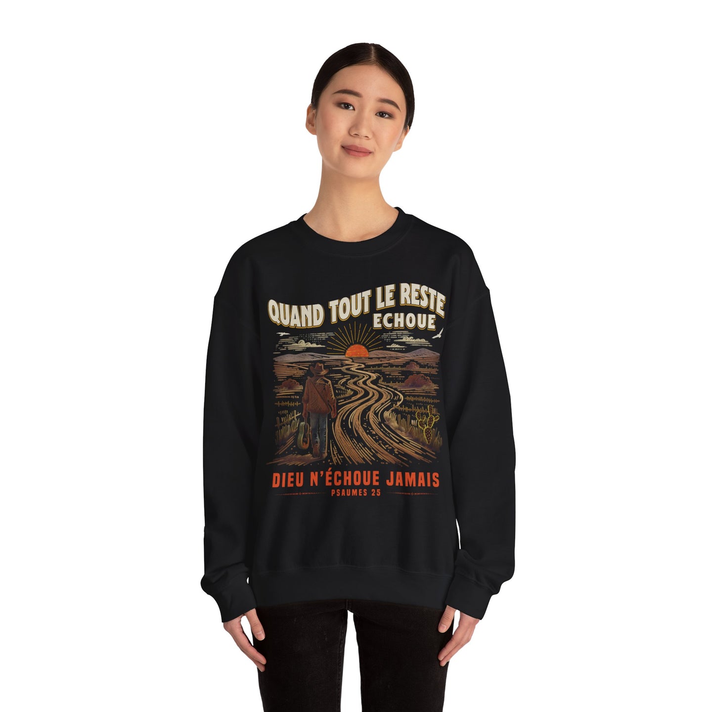 Une femme porte un sweat-shirt noir avec une illustration de paysage et un message religieux.