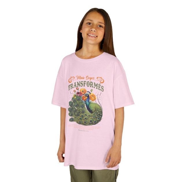 Une jeune fille porte un t-shirt rose orné d'un paon et du texte biblique Mais soyez transformés.