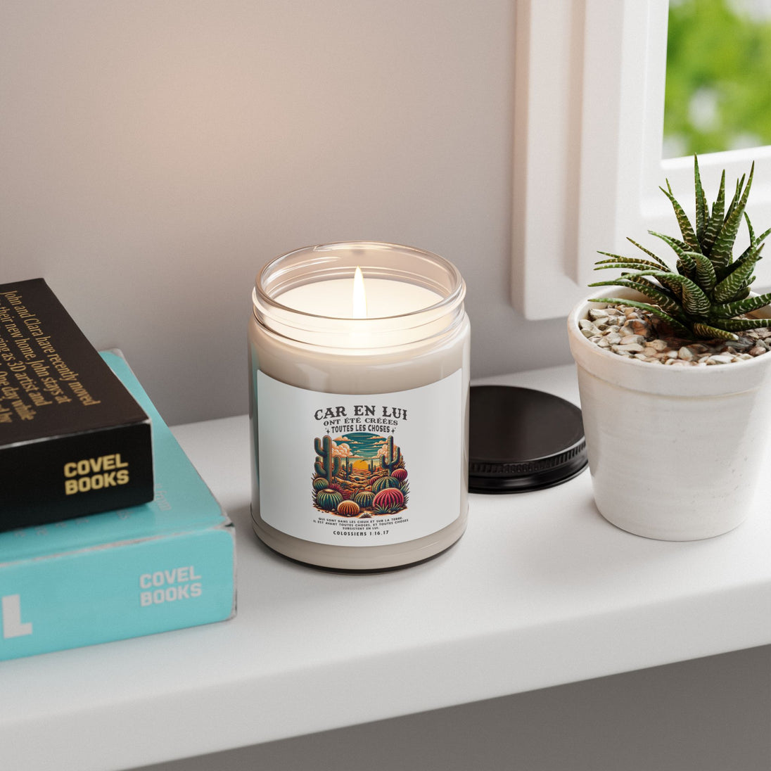 Une bougie allumée dans un pot en verre avec une étiquette illustrée de cactus sur une étagère.
