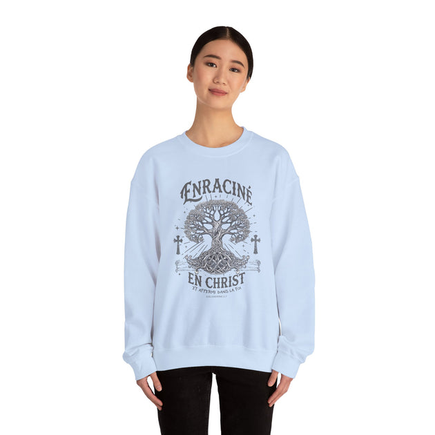 Une femme porte un sweat-shirt blanc avec un motif d'arbre de vie et le texte Enraciné en Christ.