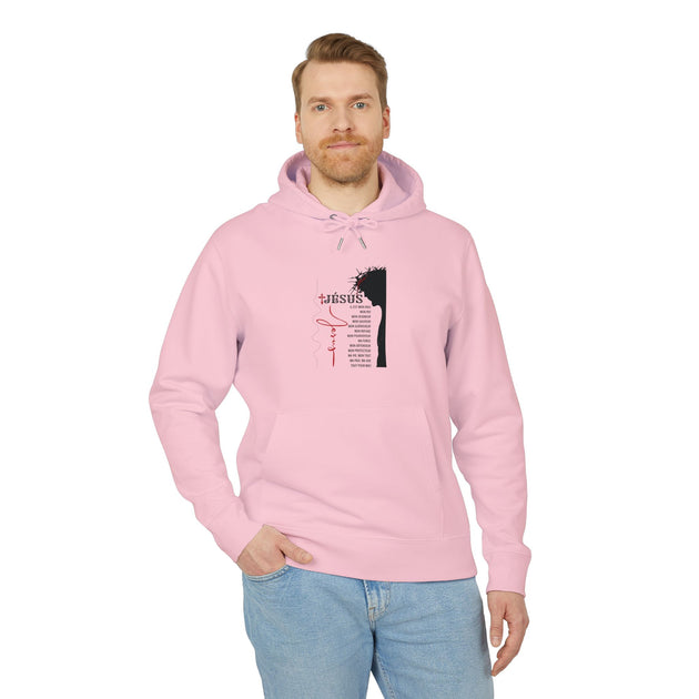 Un homme porte un sweat à capuche rose pâle avec une illustration religieuse sur la poitrine.