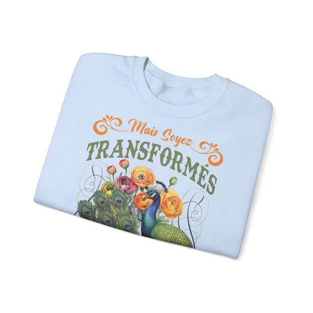 Sweat-shirt bleu clair plié avec une illustration de paon, de fleurs et le texte Mais soyez transformés.